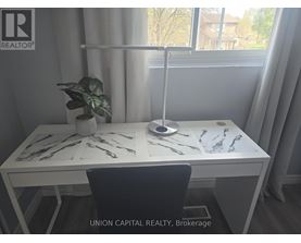 A desk with a plant and a lamp in a room with a window.