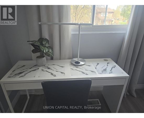 A desk with a plant and a lamp in a room with a window.