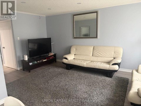 A living room with a white couch and a flat screen TV.