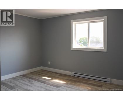 A room with a window and a radiator on the floor.
