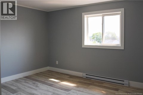 A room with a window and a radiator on the floor.