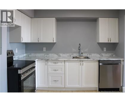 A kitchen with white cabinets and a marble countertop.