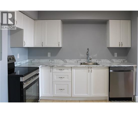 A kitchen with white cabinets and a marble countertop.