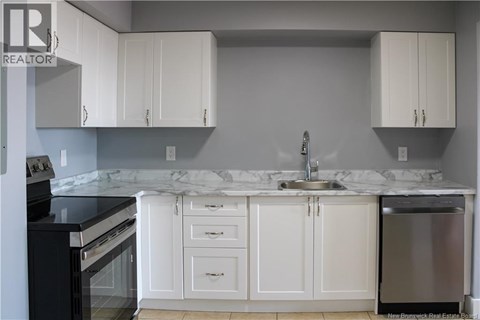 A kitchen with white cabinets and a marble countertop.