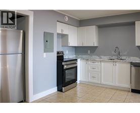 A kitchen with white cabinets and a marble countertop.