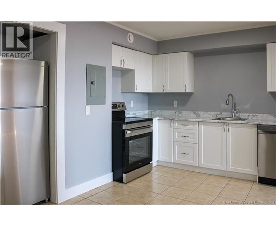 A kitchen with white cabinets and a marble countertop.