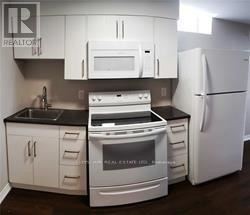 A white kitchen with a stove, oven, microwave, and refrigerator.