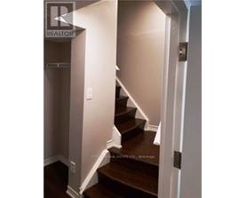 A stairway with a white wall on the left and a white door on the right.