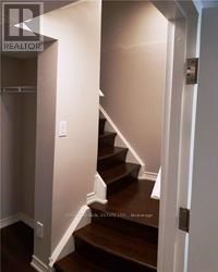 A stairway with a white wall on the left and a white door on the right.