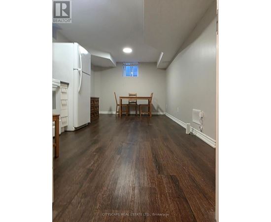 A kitchen with a white refrigerator and wooden floors.