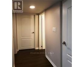 A hallway with a door on the right and a light switch on the wall.