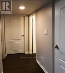 A hallway with a door on the right and a light switch on the wall.
