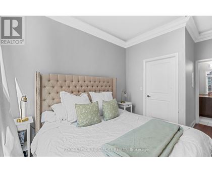 A bedroom with a large bed and a white headboard.