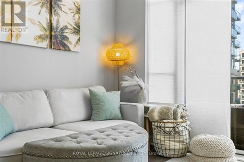 A living room with a white couch and a yellow lamp.