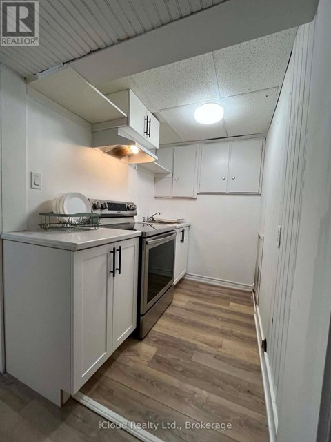 A kitchen with white cabinets and a wooden floor.