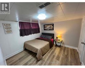 A bedroom with a bed, a nightstand with a lamp, and a framed picture on the wall.