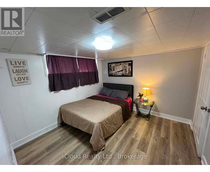 A bedroom with a bed, a nightstand with a lamp, and a framed picture on the wall.