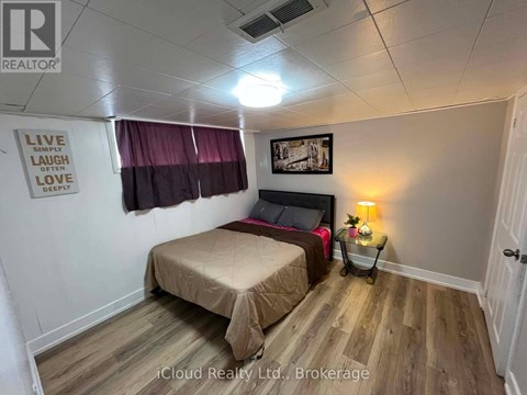 A bedroom with a bed, a nightstand with a lamp, and a framed picture on the wall.