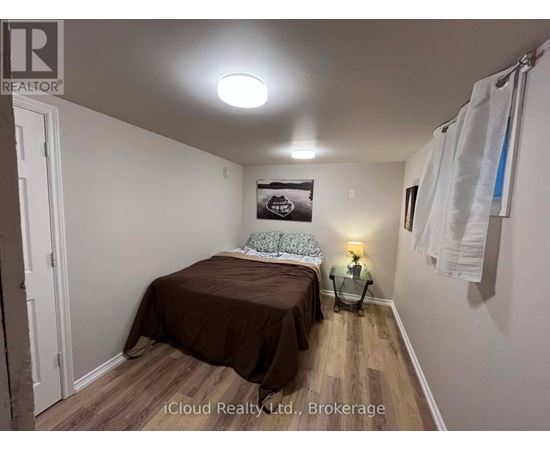 A bedroom with a bed, a nightstand, and a lamp.