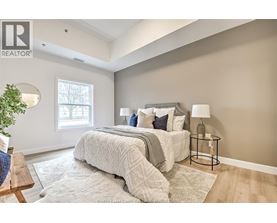 A bedroom with a large bed and a small table with a lamp.