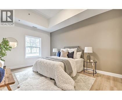 A bedroom with a large bed and a small table with a lamp.