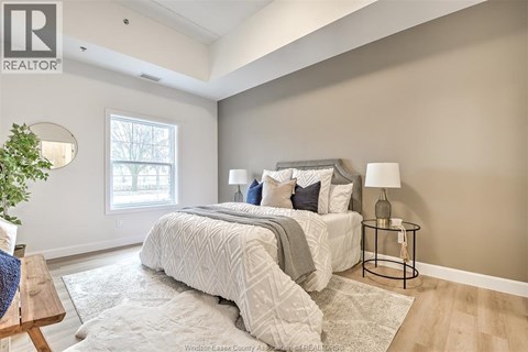 A bedroom with a large bed and a small table with a lamp.