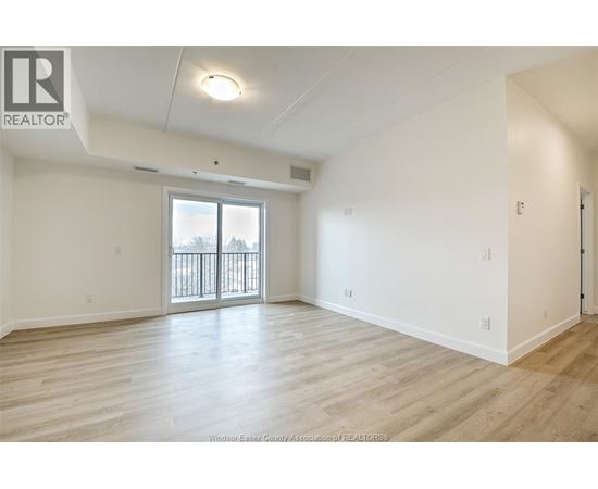 A spacious room with a sliding glass door and wooden flooring.