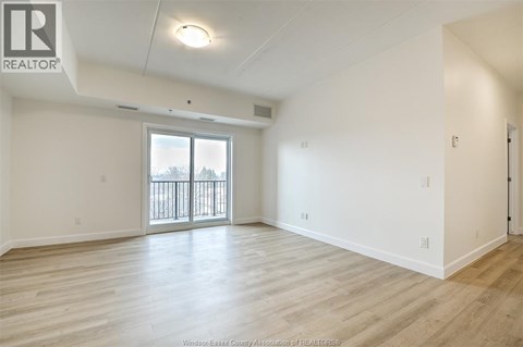 A spacious room with a sliding glass door and wooden flooring.