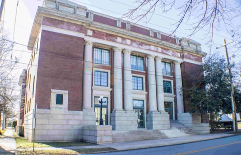 A red brick building with white columns and a green door.