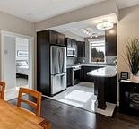 A kitchen with a black refrigerator and a wooden table.