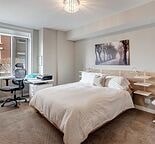 A bedroom with a large bed and a desk with a chair.
