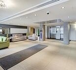 A spacious living room with a green couch and a grey rug.