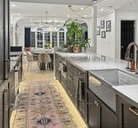 A kitchen with a rug on the floor and a table with chairs.