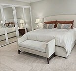 A white bed with a white headboard and pillow with a white bedroom.