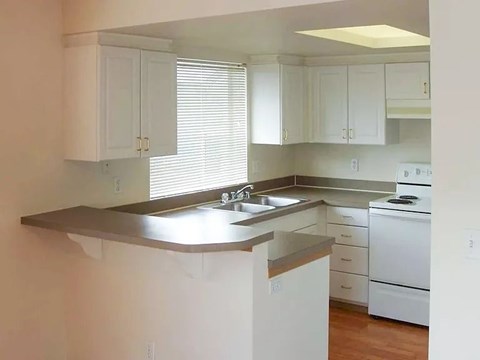 A kitchen with white cabinets and a stainless steel sink.