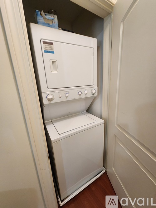 A white dishwasher is installed in a narrow space between a wall and a door.