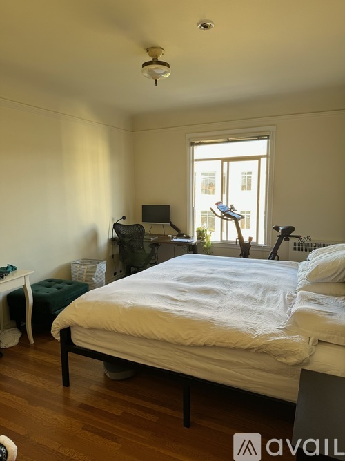 A bedroom with a bed, a window, and a desk with a lamp.