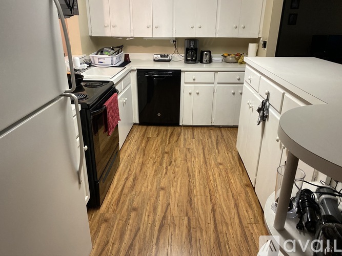 A kitchen with white cabinets and a wooden floor.