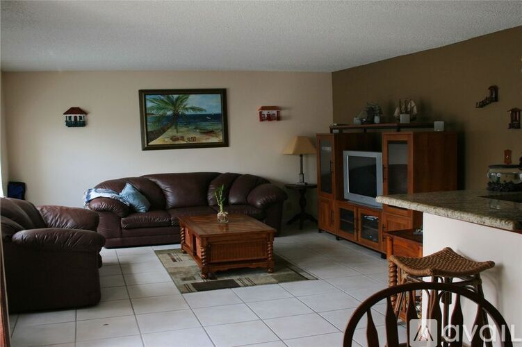 A living room with brown leather furniture and a painting of a beach scene on the wall.