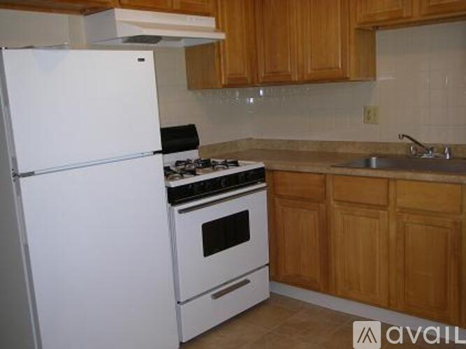 A kitchen with a white refrigerator, white stove, and wooden cabinets.