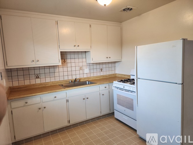 A kitchen with white cabinets and a white fridge.