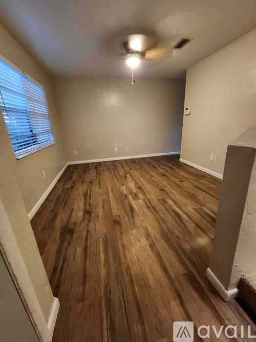 A room with wooden flooring and a window with blinds.
