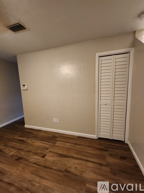 A room with a white door and wooden floor.