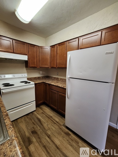 A kitchen with white appliances and wooden cabinets.
