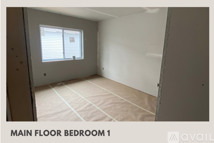 A bedroom with a window and a bedspread on the floor.