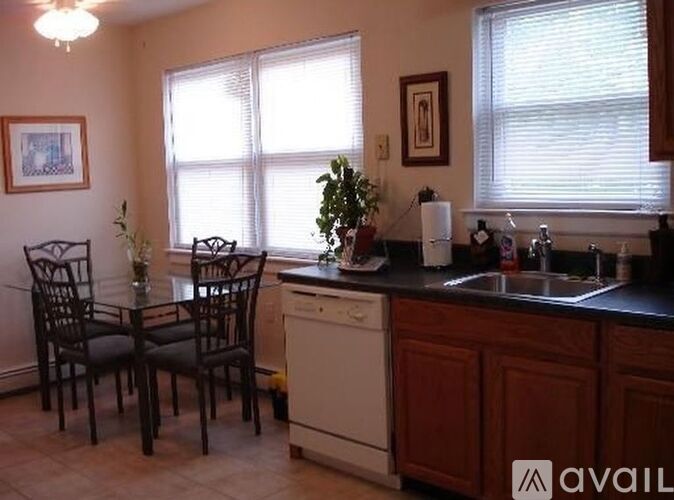 A kitchen with a white dishwasher and dark wood cabinets.