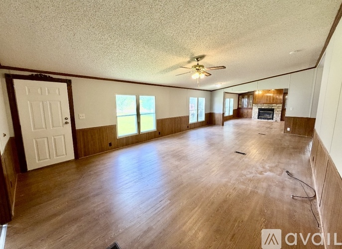 A spacious room with wood flooring and a ceiling fan.