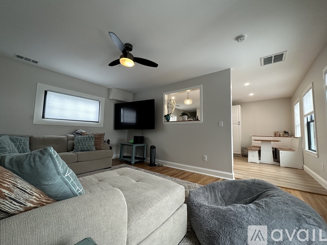 A living room with a grey couch and a flat screen TV mounted on the wall.