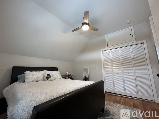 A bedroom with a bed, a ceiling fan, and a wardrobe.
