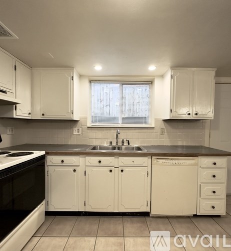 A kitchen with white cabinets and a black countertop.